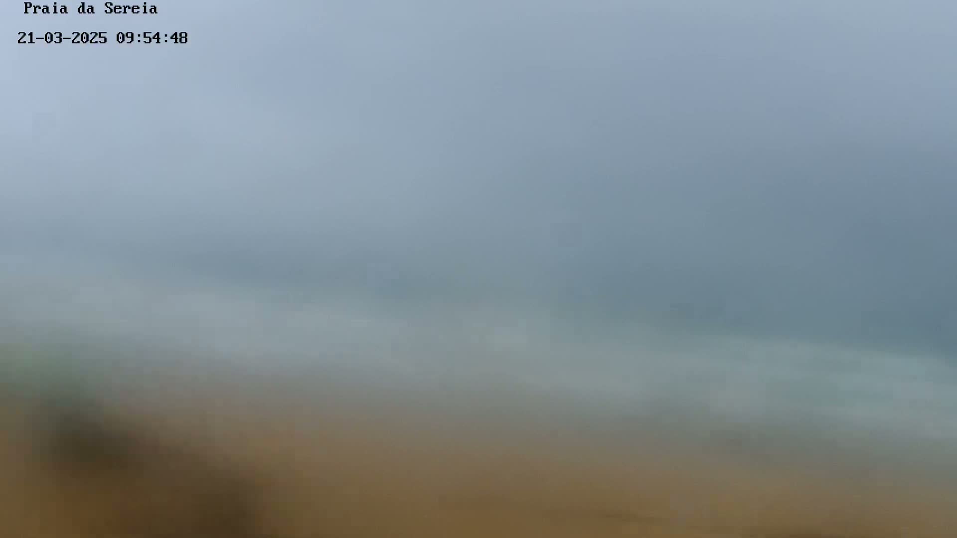 A hazy, overcast day reveals a blurry view of a beach and ocean.
