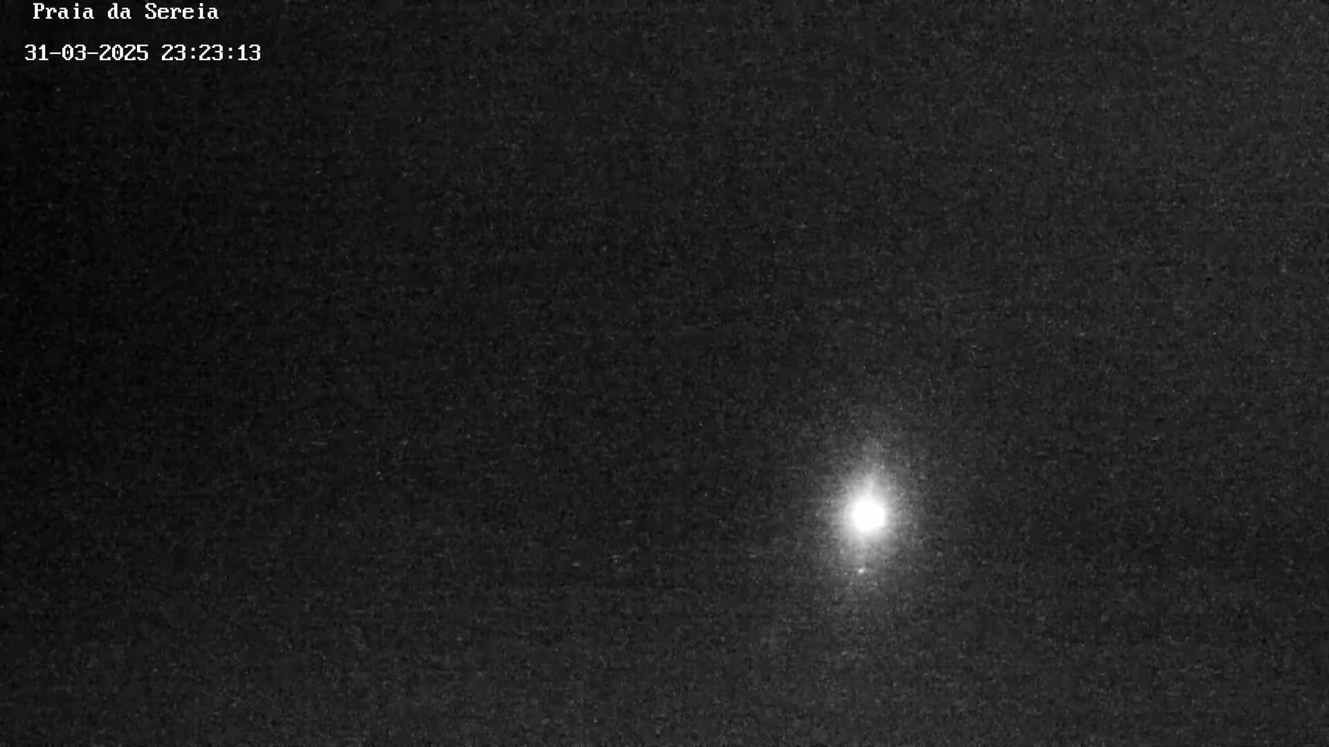 A bright light is visible in the center of a dark, nighttime sky.