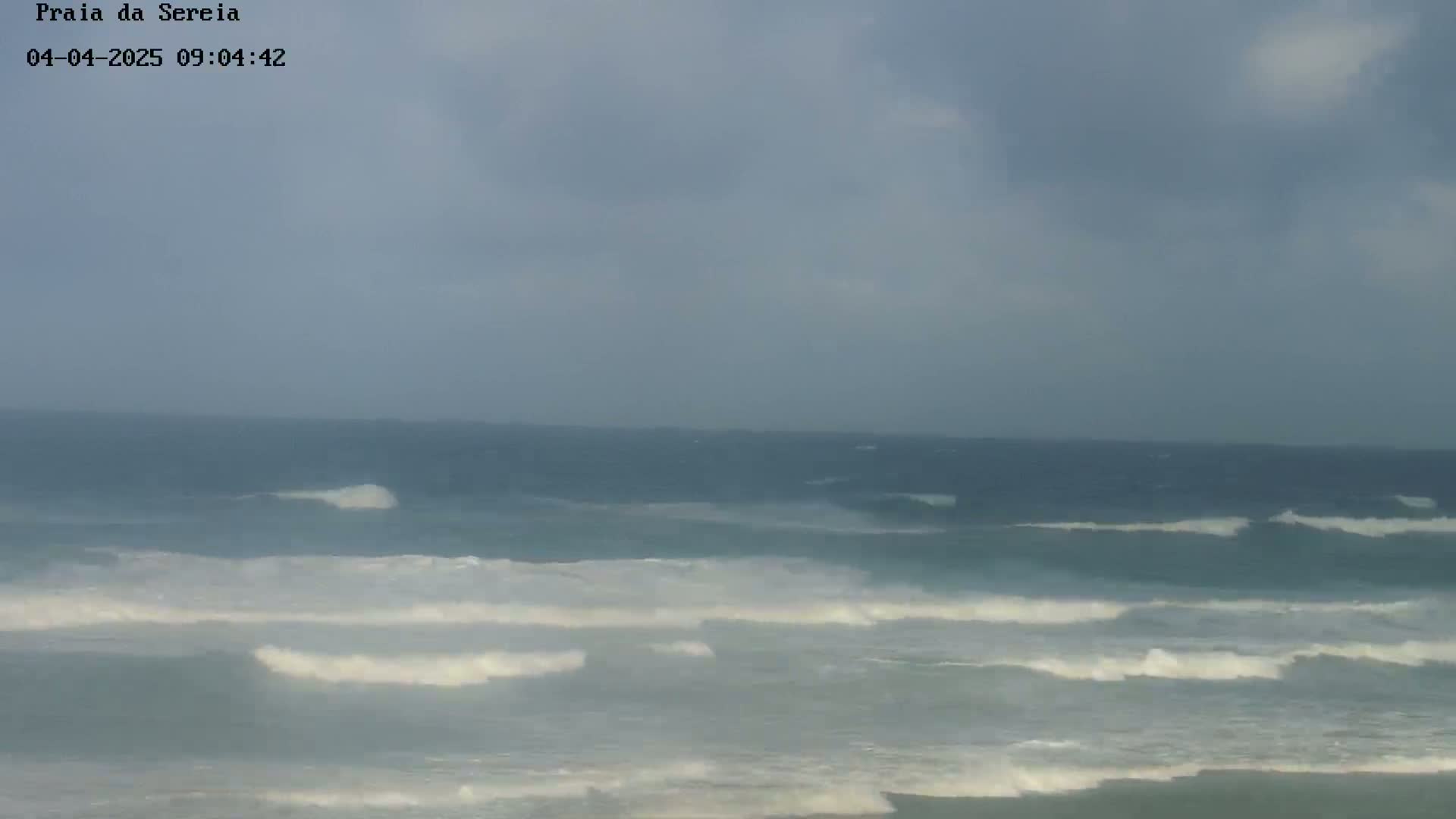 A wide shot of an ocean with moderate waves under an overcast sky.