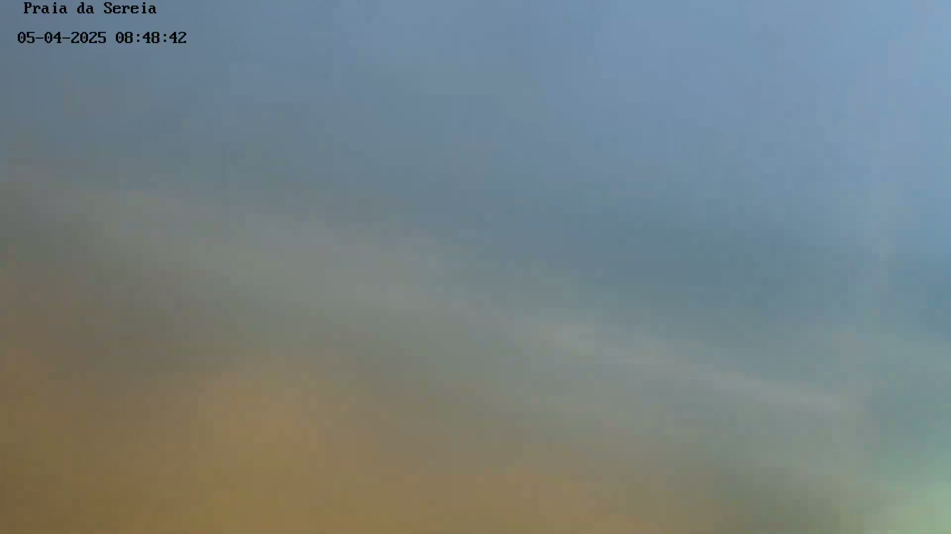A hazy, muted-toned sky shows a gradient of blue, gray, and tan.