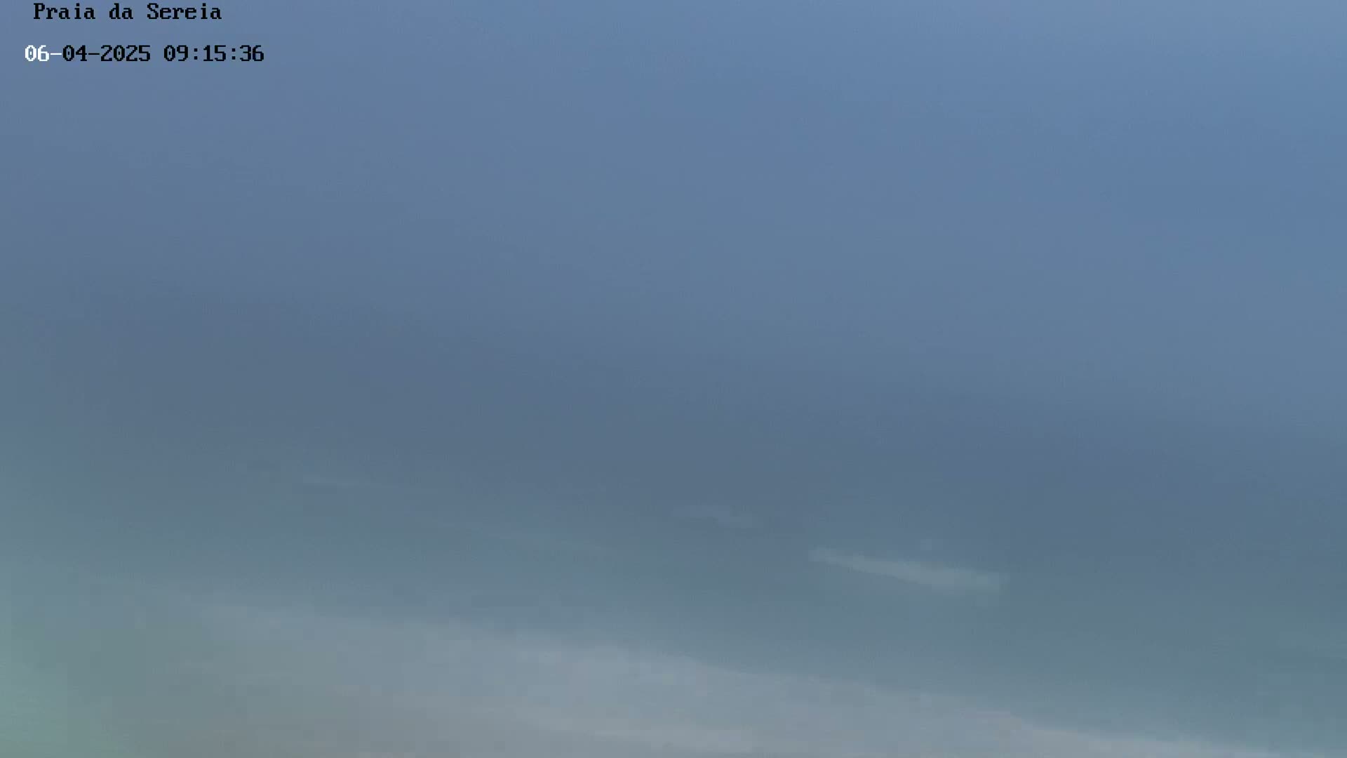A hazy, foggy scene shows a mostly featureless expanse of water or land under an overcast sky.