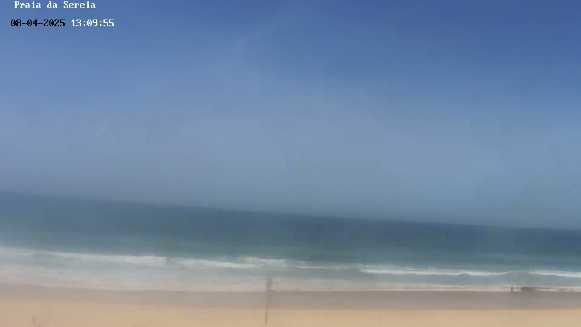 A long sandy beach and ocean are visible under a clear blue sky.