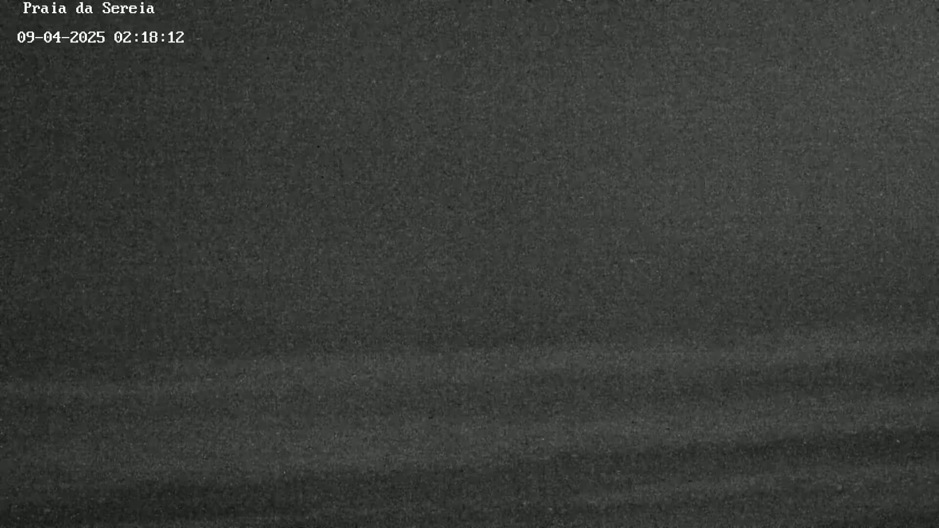 A dark gray, textured surface, possibly asphalt, is shown under nighttime conditions.