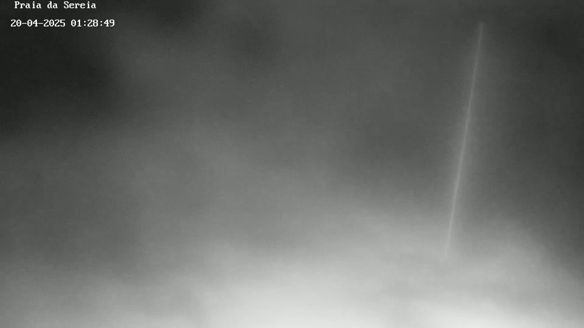 A long, thin, bright streak appears in a hazy, overcast sky.