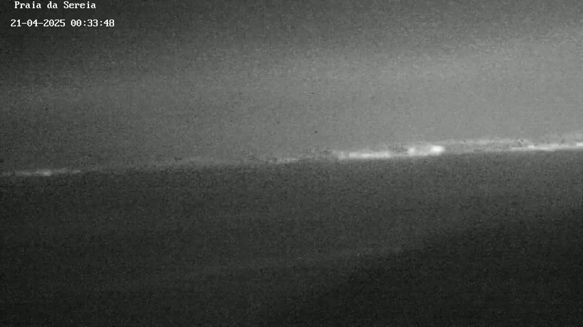 A low-light image shows a dark, possibly nighttime, scene with a faint line of light on the horizon.