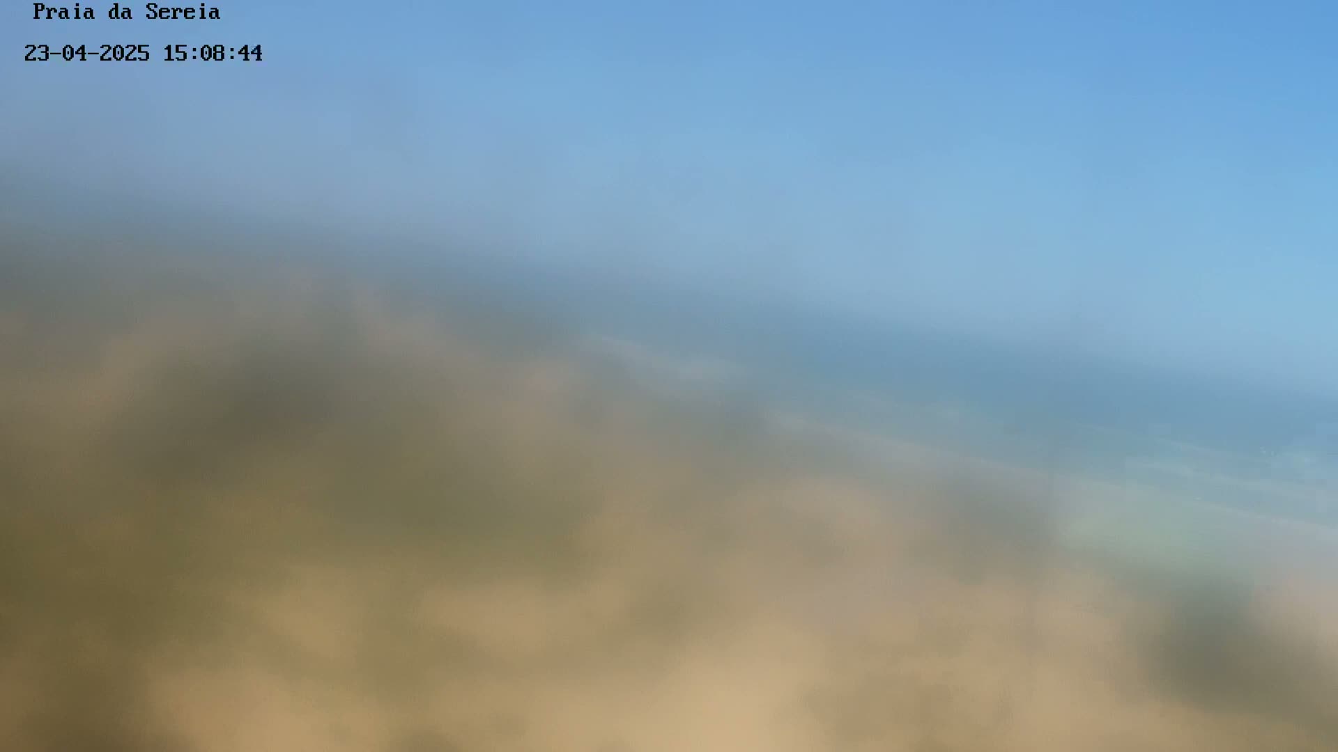 A blurry, hazy image shows a beach scene under a clear blue sky.