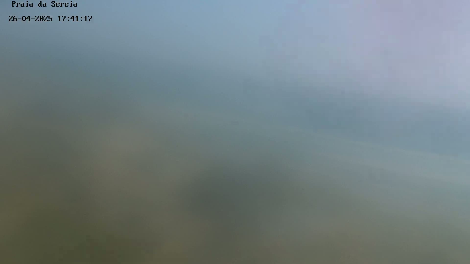 A hazy, blurry view of a muted landscape under a cloudy sky.
