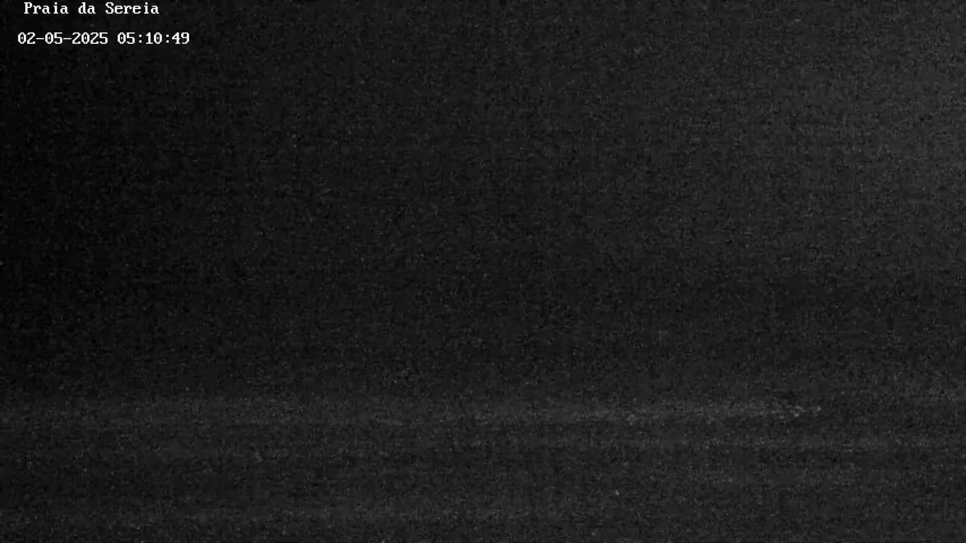 A dark, grainy image shows a mostly black scene, possibly at night or in low-light conditions.