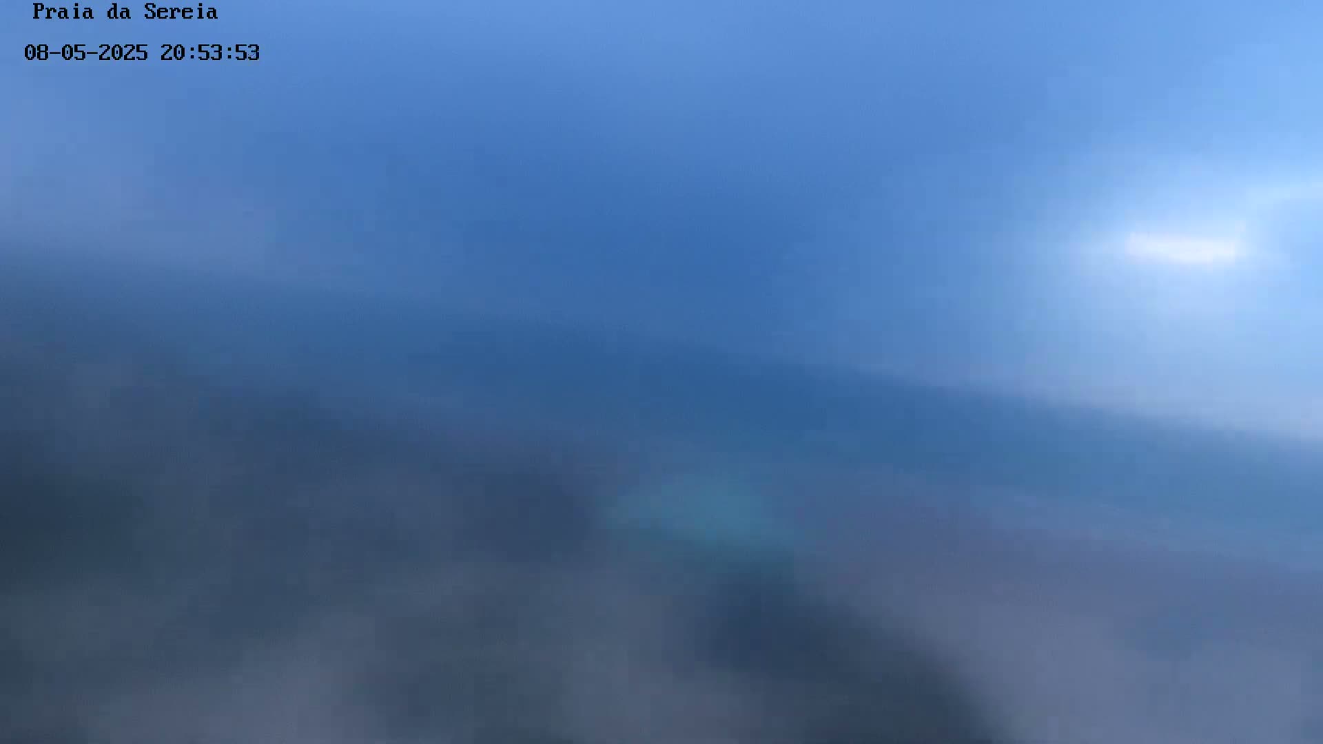 A hazy, blue sky is visible, with a hint of light in the upper right corner.