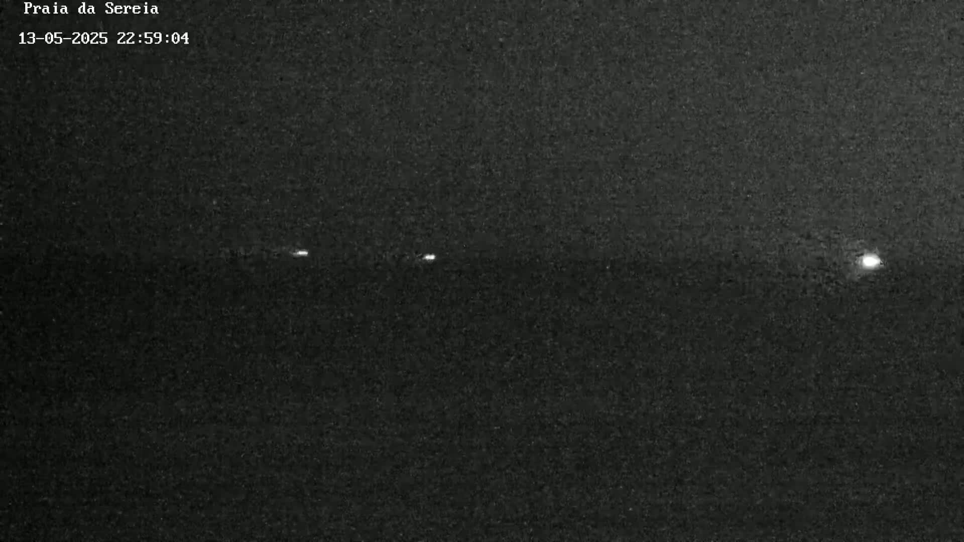 A nighttime, low-light image shows a series of faint lights aligned horizontally across a dark background.