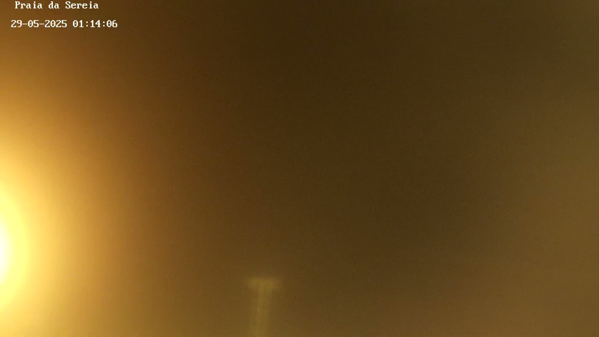 A hazy, yellowish-brown sky is visible at night, with a faint, vertical light source in the center.