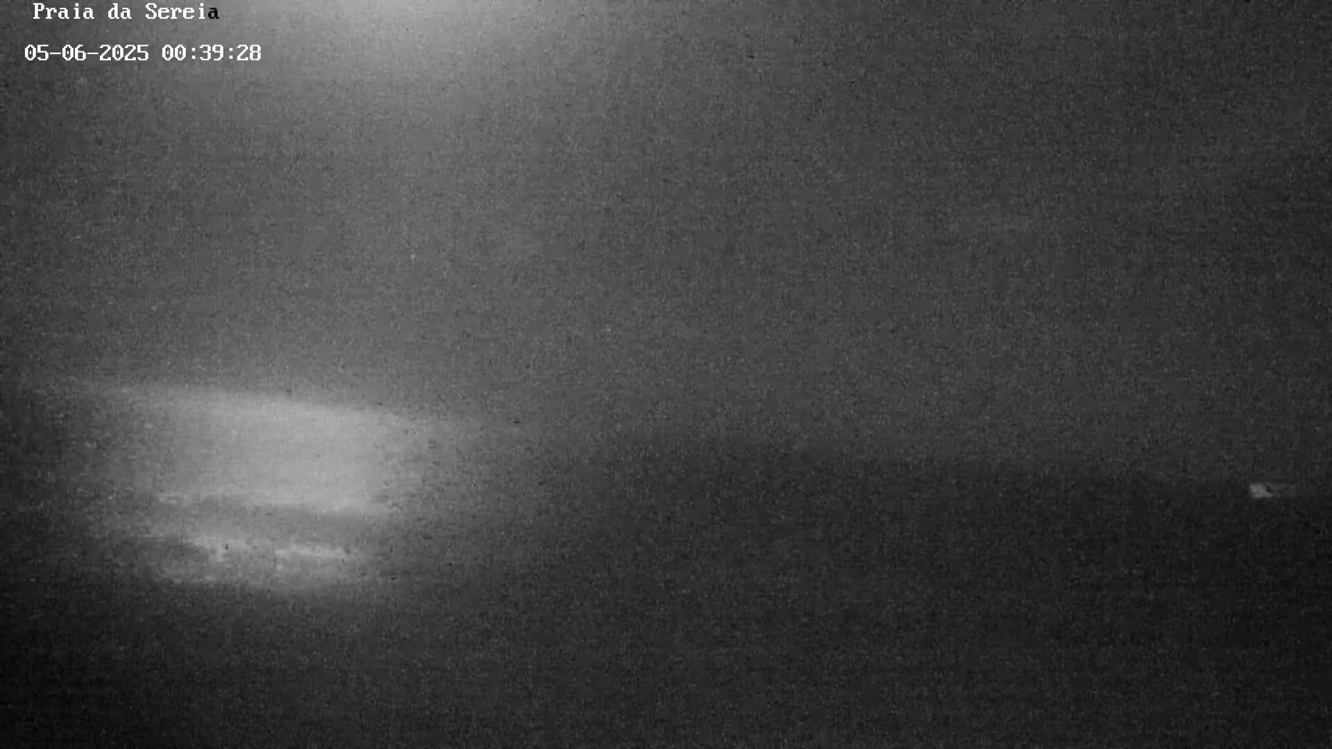 A grainy, low-light image shows a dark, possibly nighttime scene with a faintly brighter area in the lower-center.