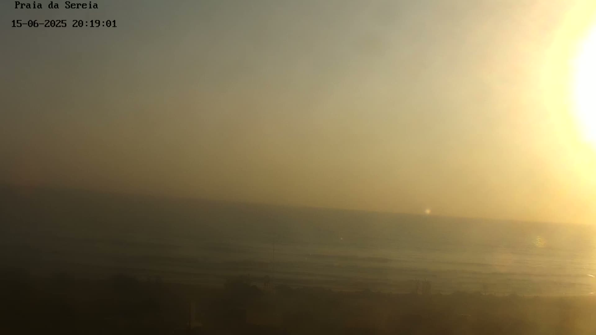 A hazy, blurry view of a sandy beach and ocean under a light blue sky.