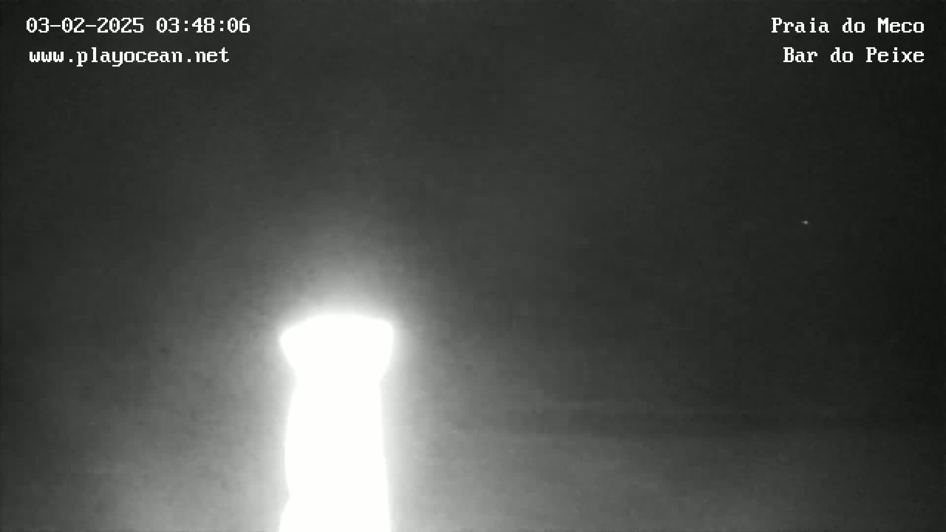 A bright, blurry light source, possibly a lighthouse, is visible against a dark, nighttime sky.