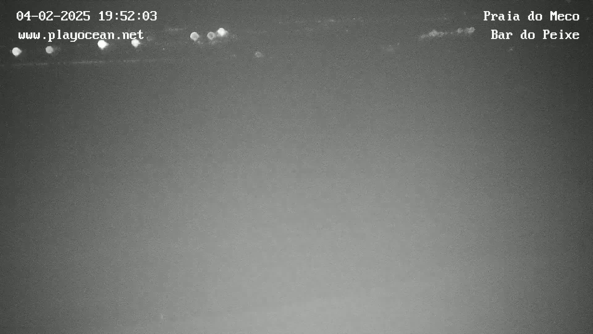 A nighttime, low-light image shows a dark gray sky with a few faint, bright spots near the top.