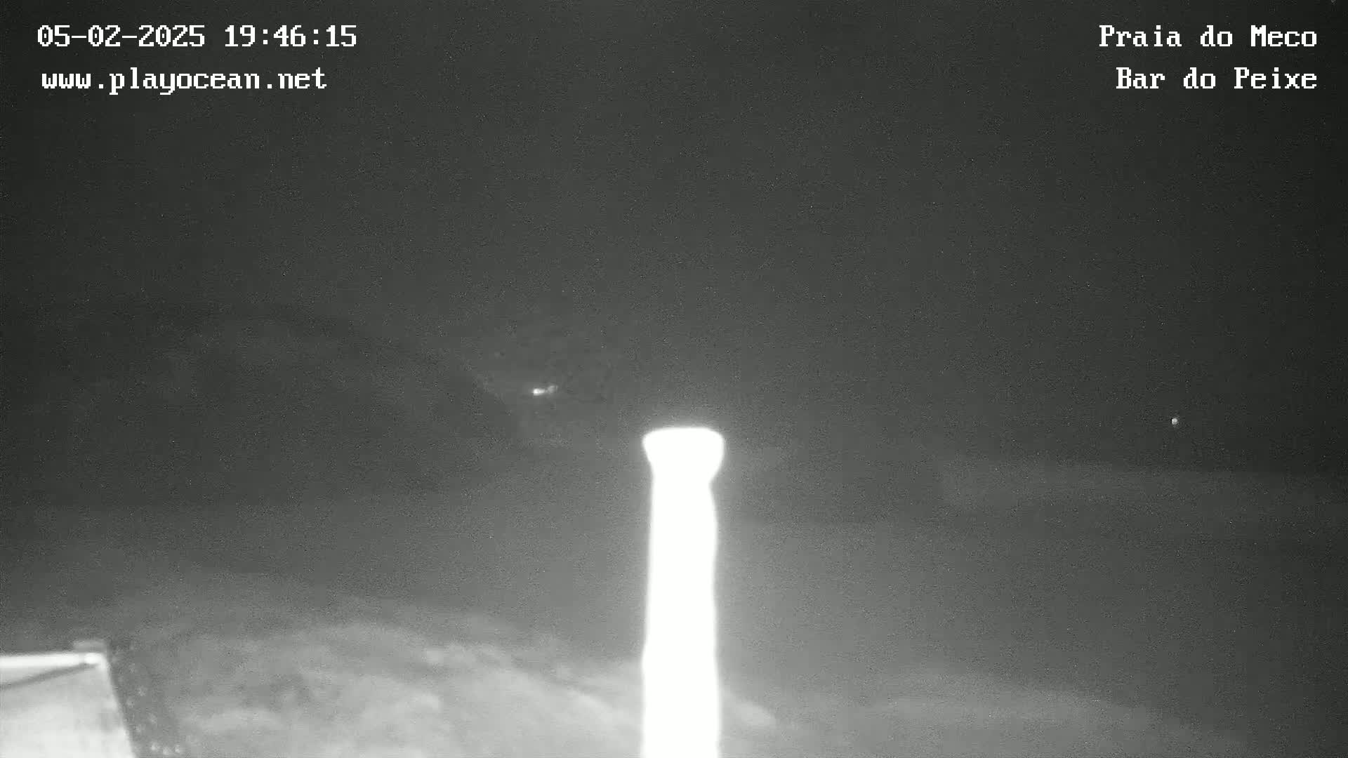 A brightly lit, tall, thin object is visible at night against a dark, mostly clear sky.