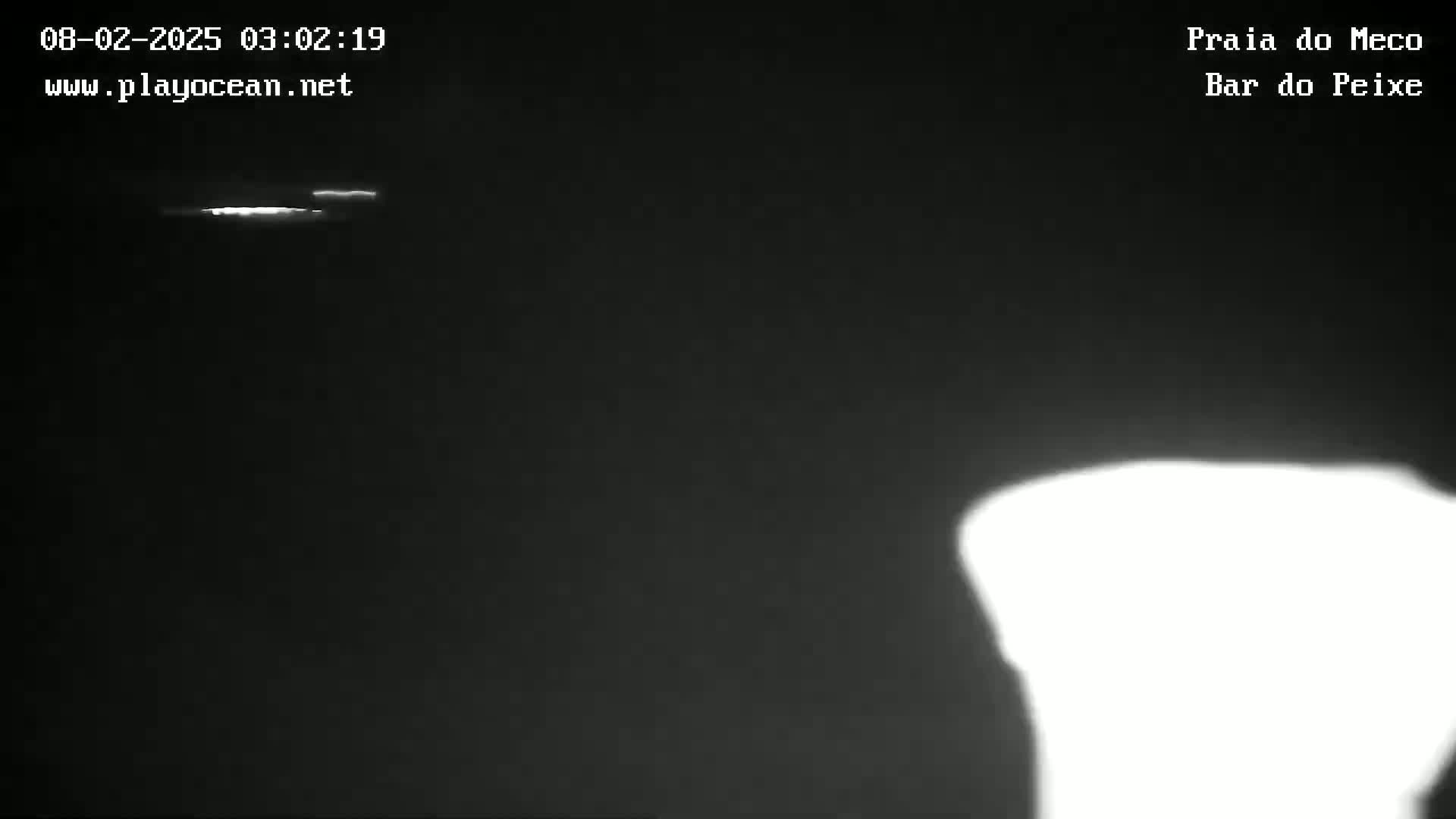 A nighttime, low-light image shows a bright light source in the distance and an overexposed bright area in the lower right corner.