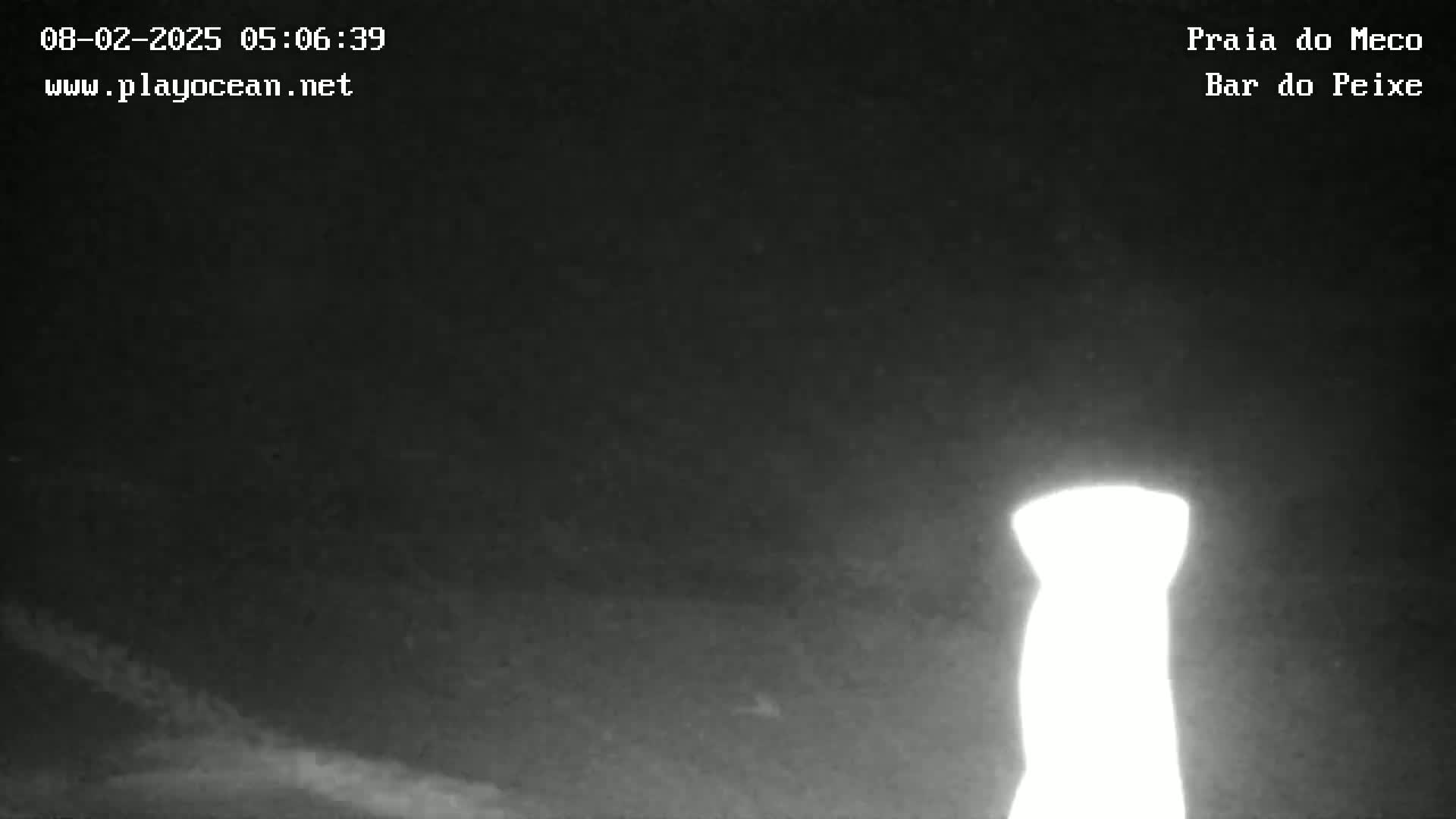A brightly lit, tall, slender object is visible against a dark, cloudy night sky.