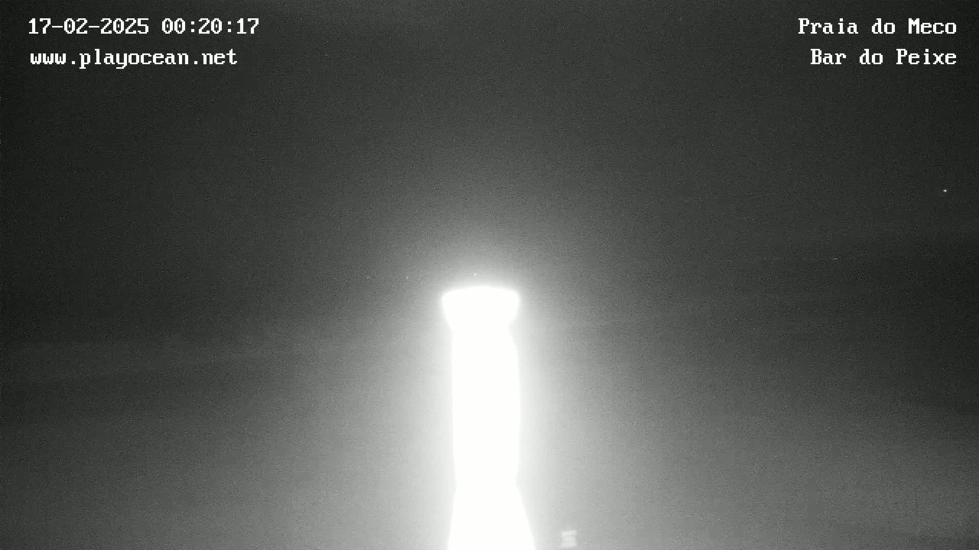 A brightly lit, tall, thin object is visible against a dark, night sky.