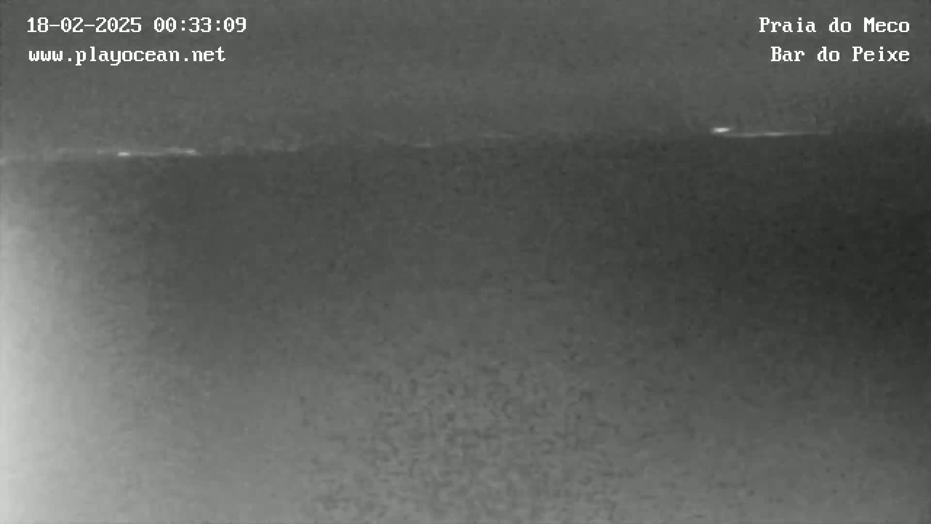 A nighttime, low-light image shows a dark ocean horizon with a faint, thin line of light possibly indicating the horizon.