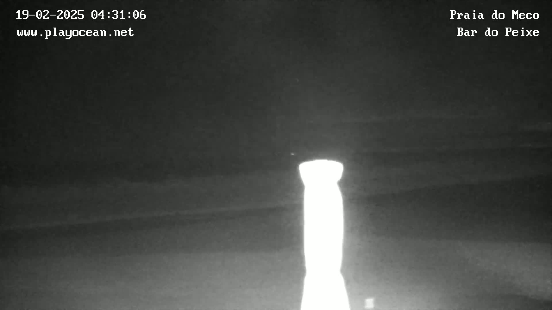 A brightly lit, tall, thin object stands out against a dark, nighttime, outdoor scene.
