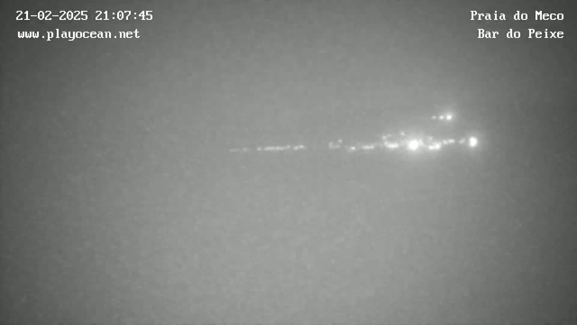A long, faint line of lights is visible on the horizon at night in hazy or foggy conditions.