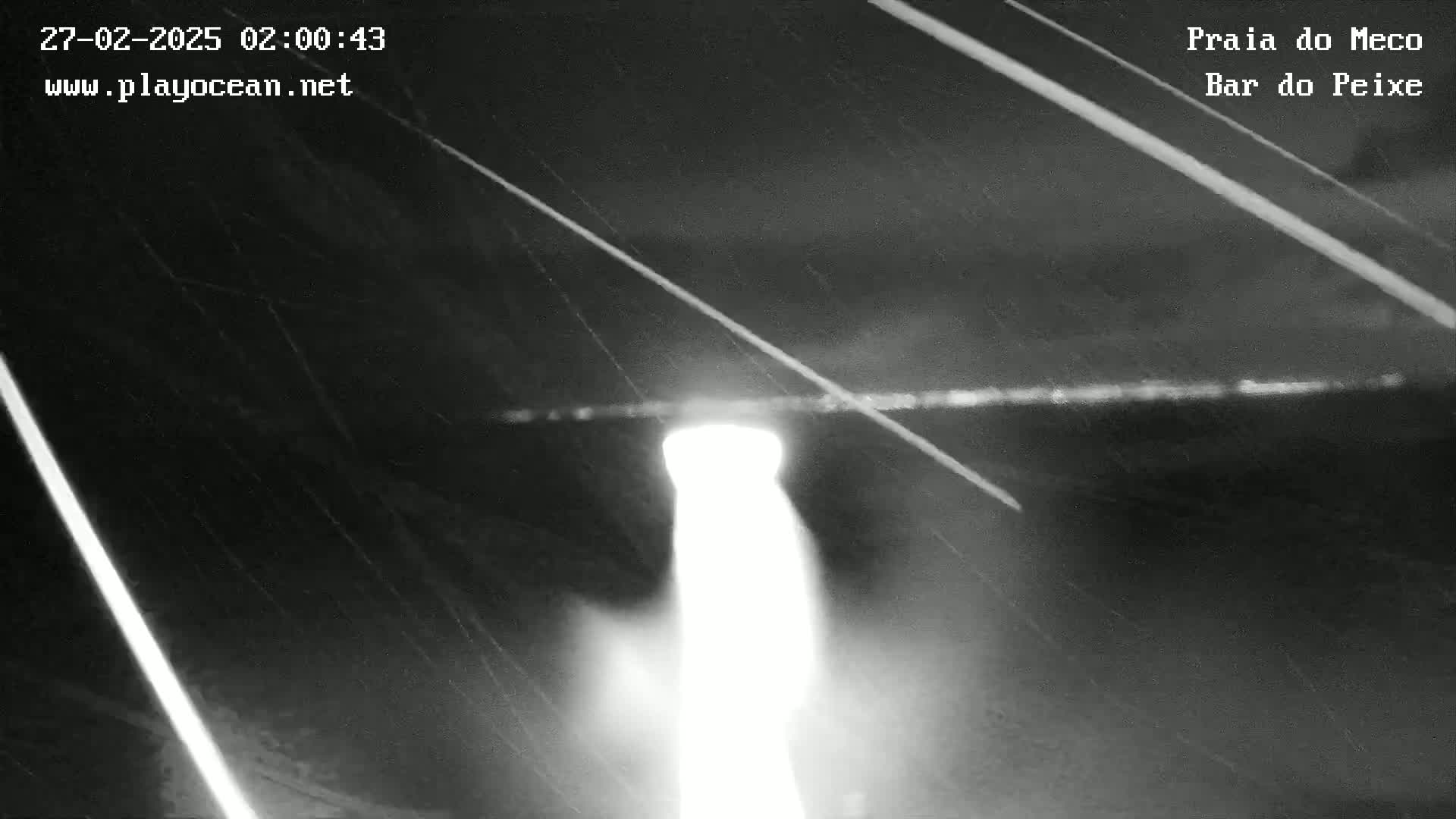 A bright light shines through what appears to be rain at night.