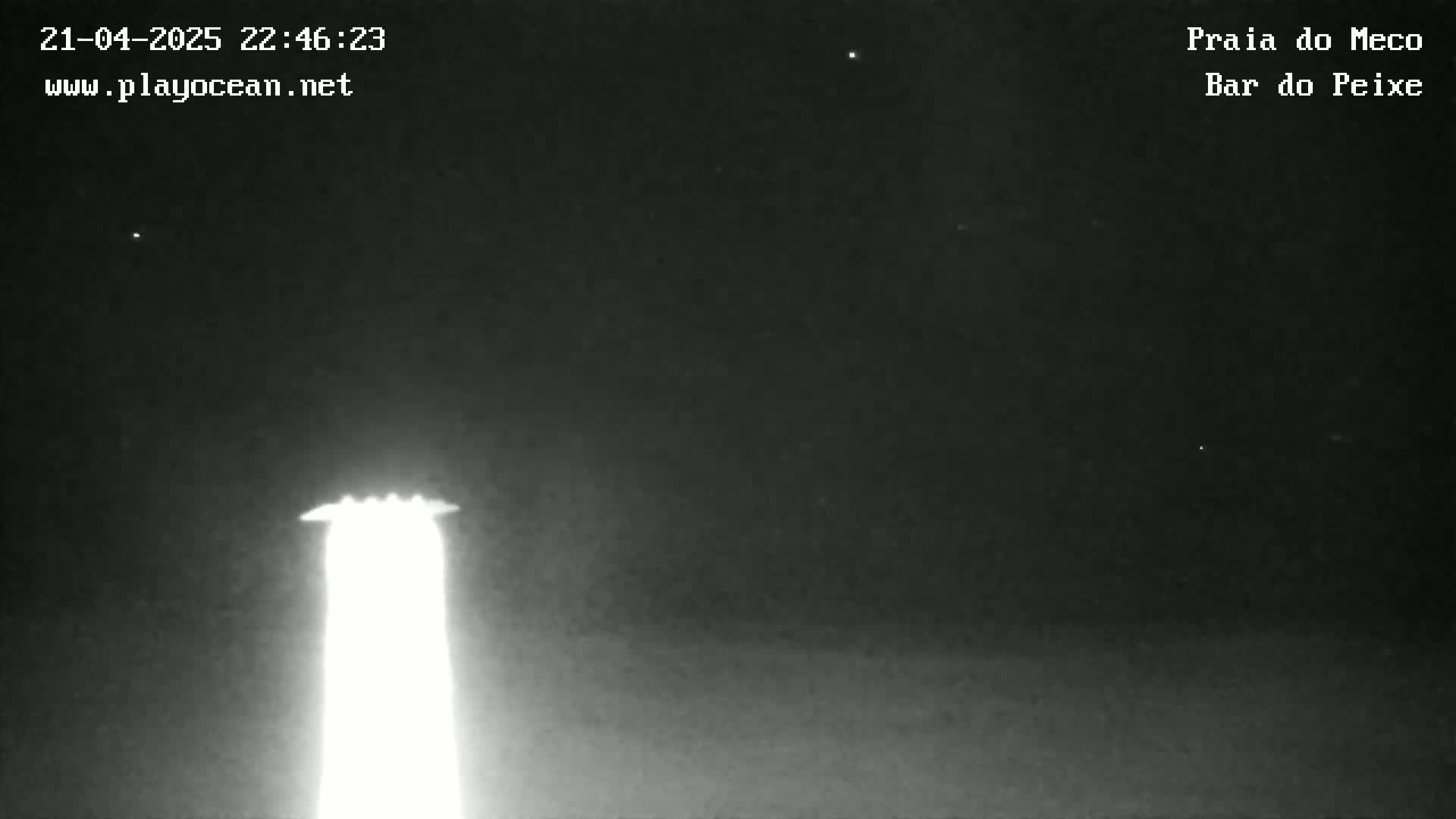A bright light, possibly a spotlight or lighthouse, illuminates the night sky.