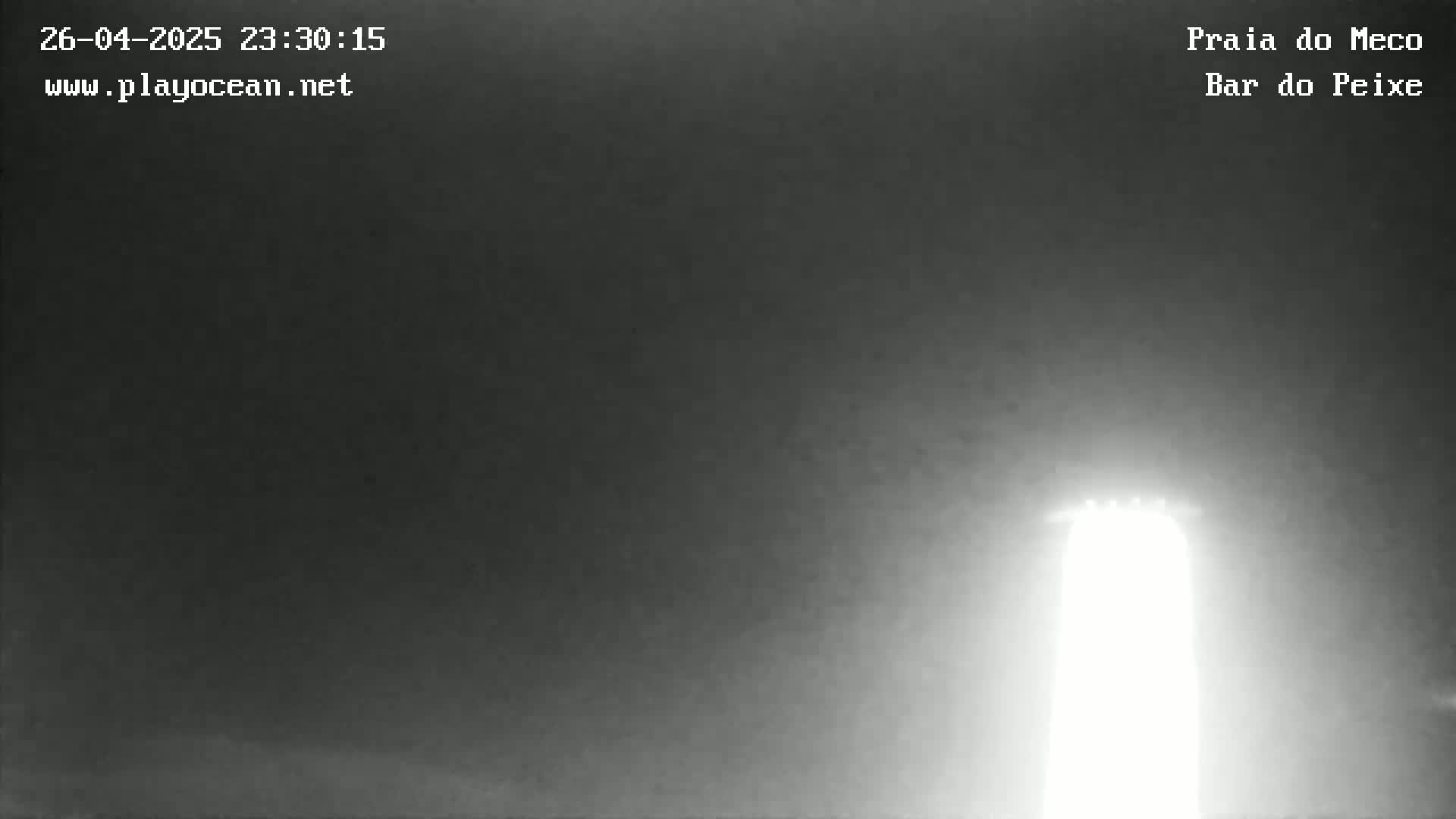 A brightly lit structure is visible in the hazy darkness of the night.