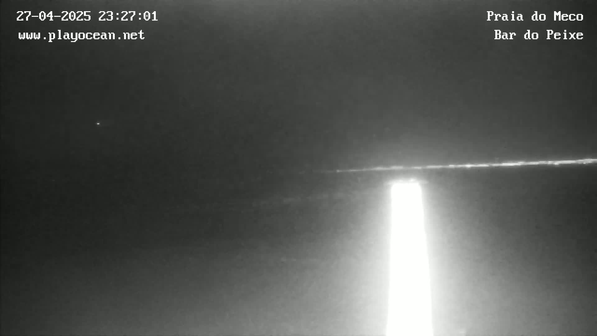 A nighttime, low-light image shows a bright vertical light source on the right, a faint horizontal line representing the horizon, and a dark sky above.