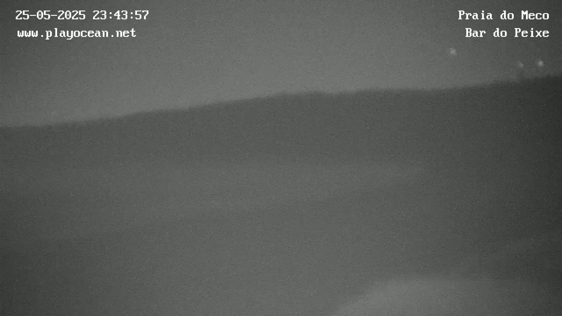 A dark, grainy nighttime image shows a mostly featureless horizon line, possibly of a beach or coastline.