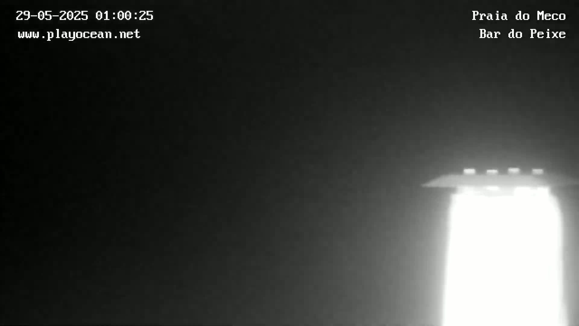 A brightly lit structure is visible in the dark, possibly at night.