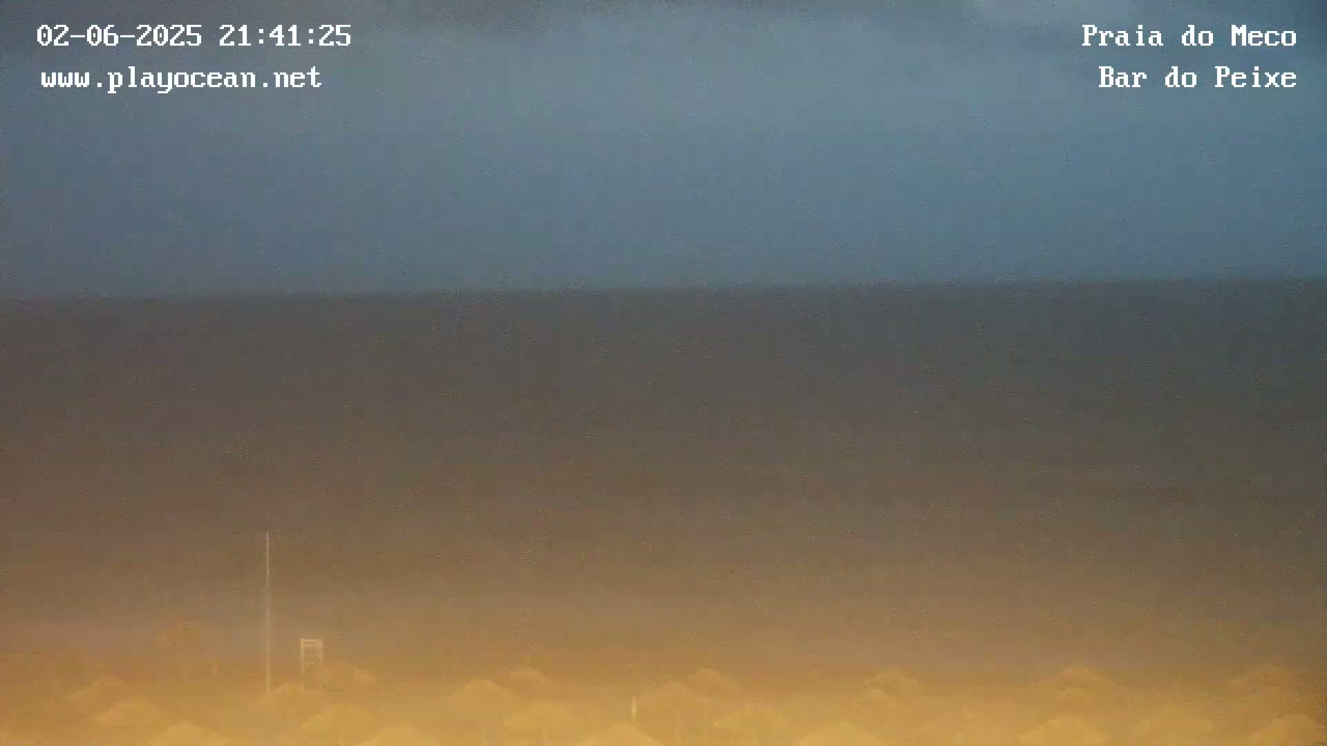 A hazy, dark-orange and grayish-blue ocean is visible under a dark, overcast sky.