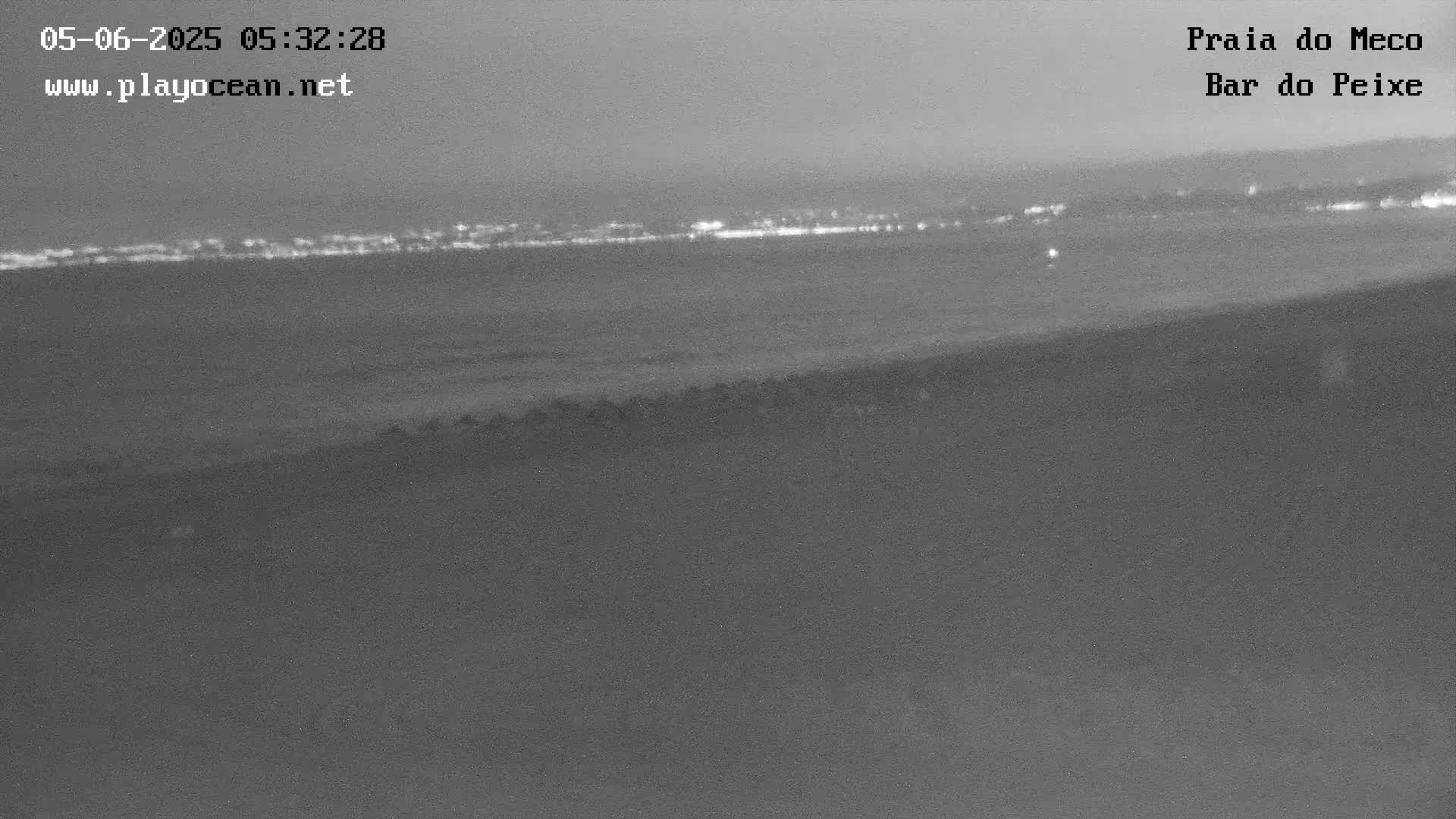 A nighttime, low-light view shows a dark body of water with a distant, faintly lit shoreline.