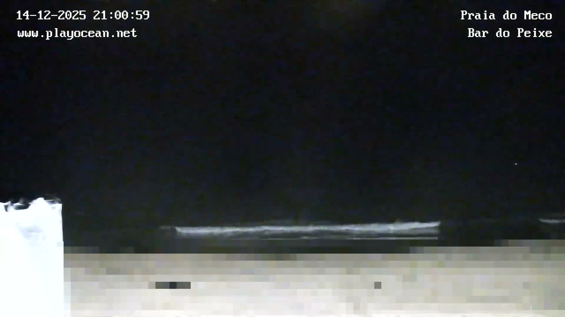 A very dark and pixelated outdoor night scene depicts a dimly discernible shoreline with faint horizontal lines, possibly waves, under a clear dark sky.