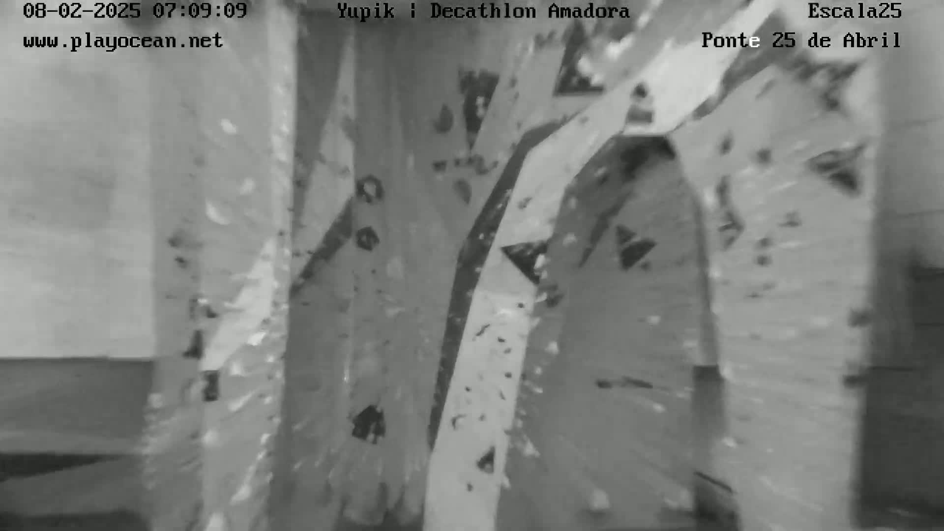 A blurry grayscale image shows an indoor climbing wall with various holds.