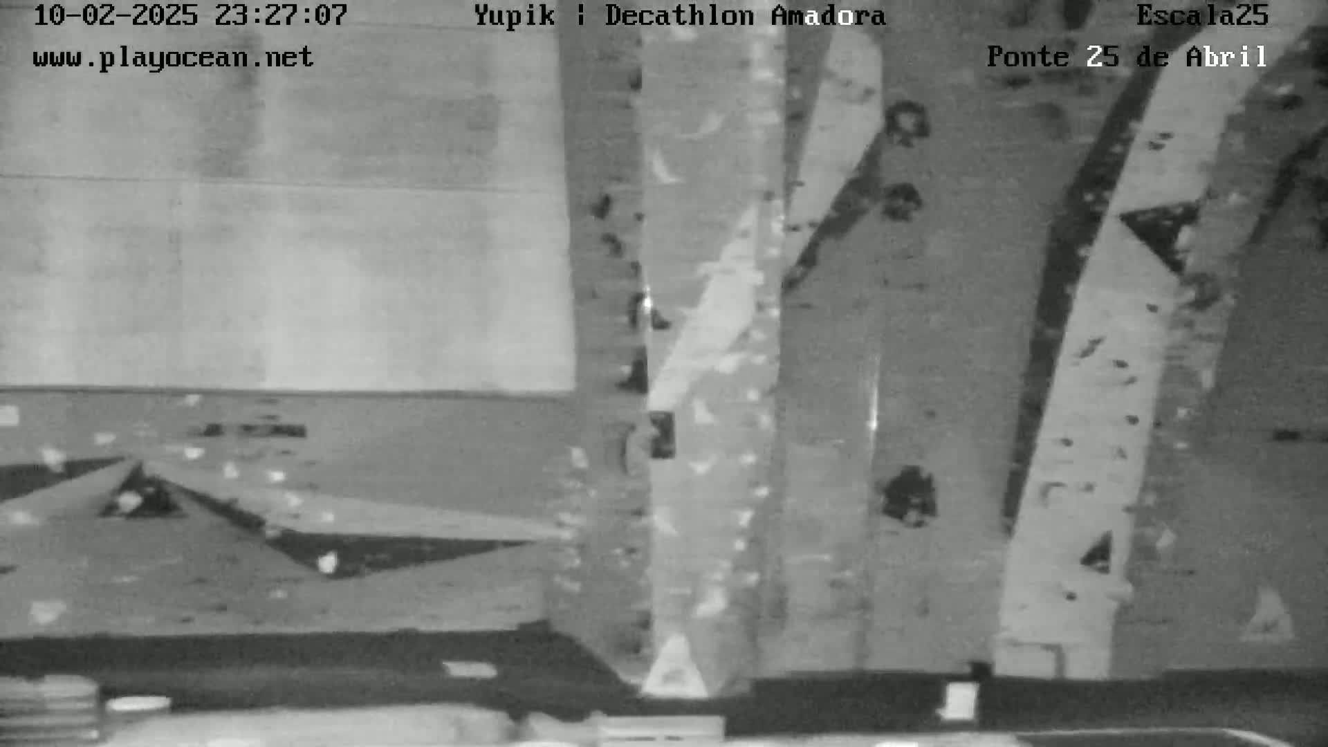 A grainy, black and white image shows an indoor climbing wall with various handholds and footholds.