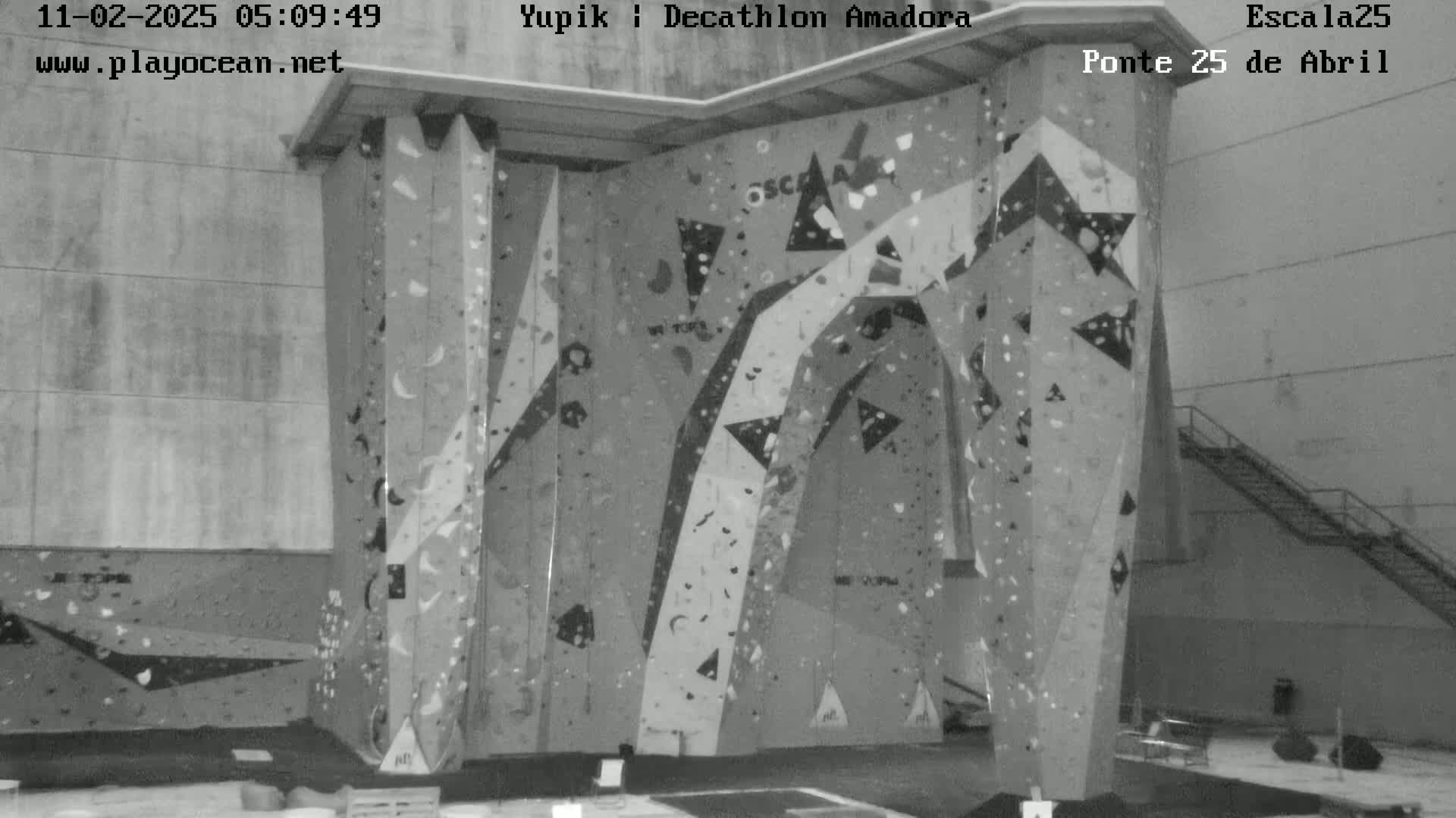 A large indoor climbing wall with various holds and patterns is shown in a grayscale image.