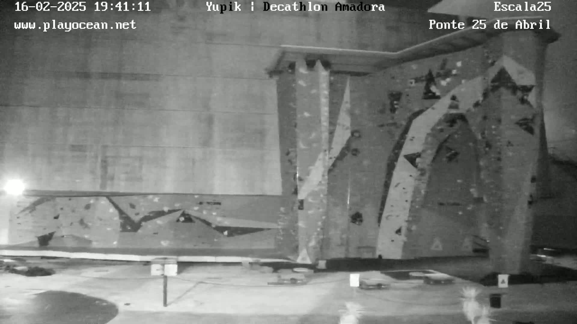 A nighttime, black and white view of an outdoor climbing wall.