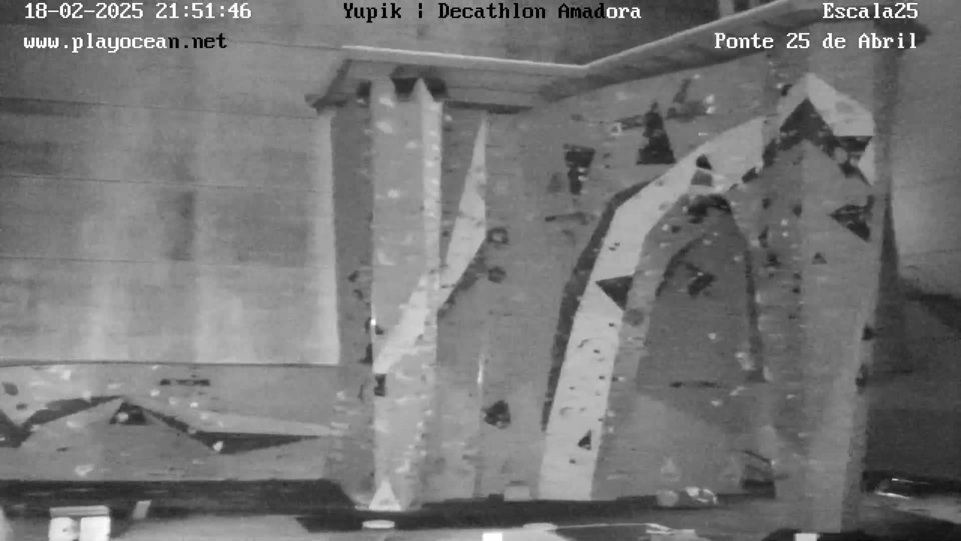 A grayscale image shows an indoor climbing wall with various angled holds.