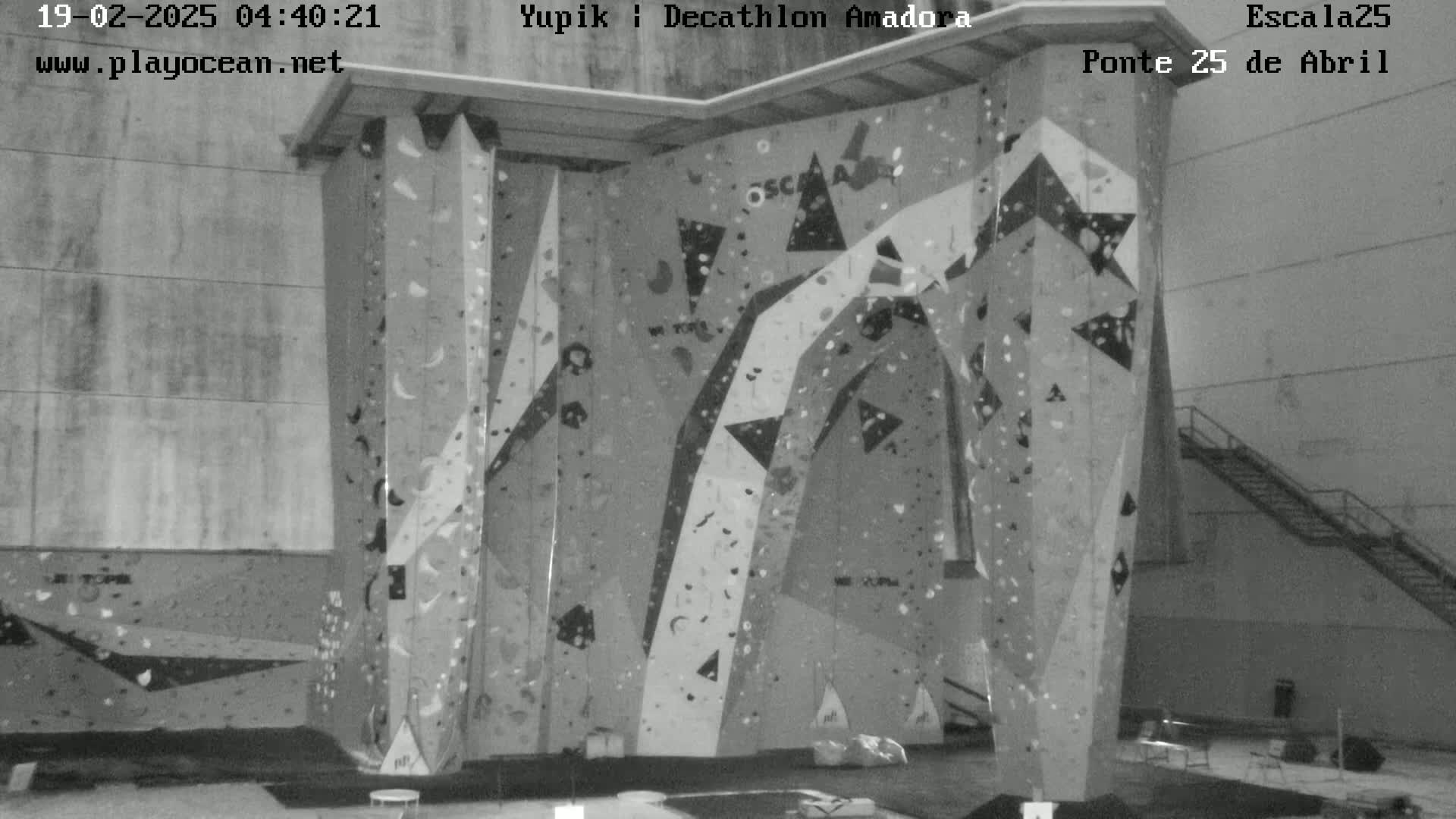 A grayscale image shows an indoor climbing wall with various holds and patterns.