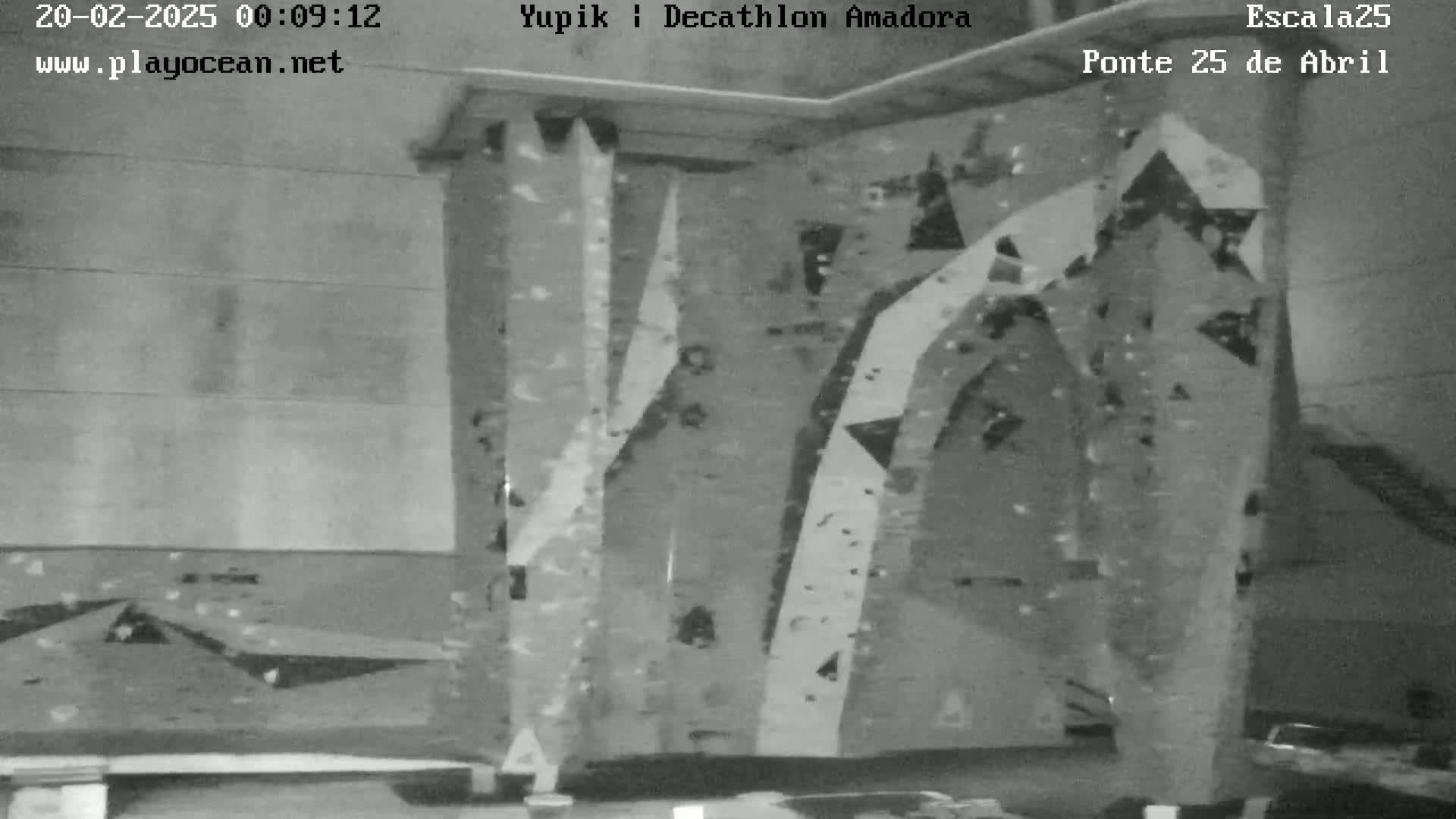 A grayscale image shows an indoor climbing wall with various holds and angles.