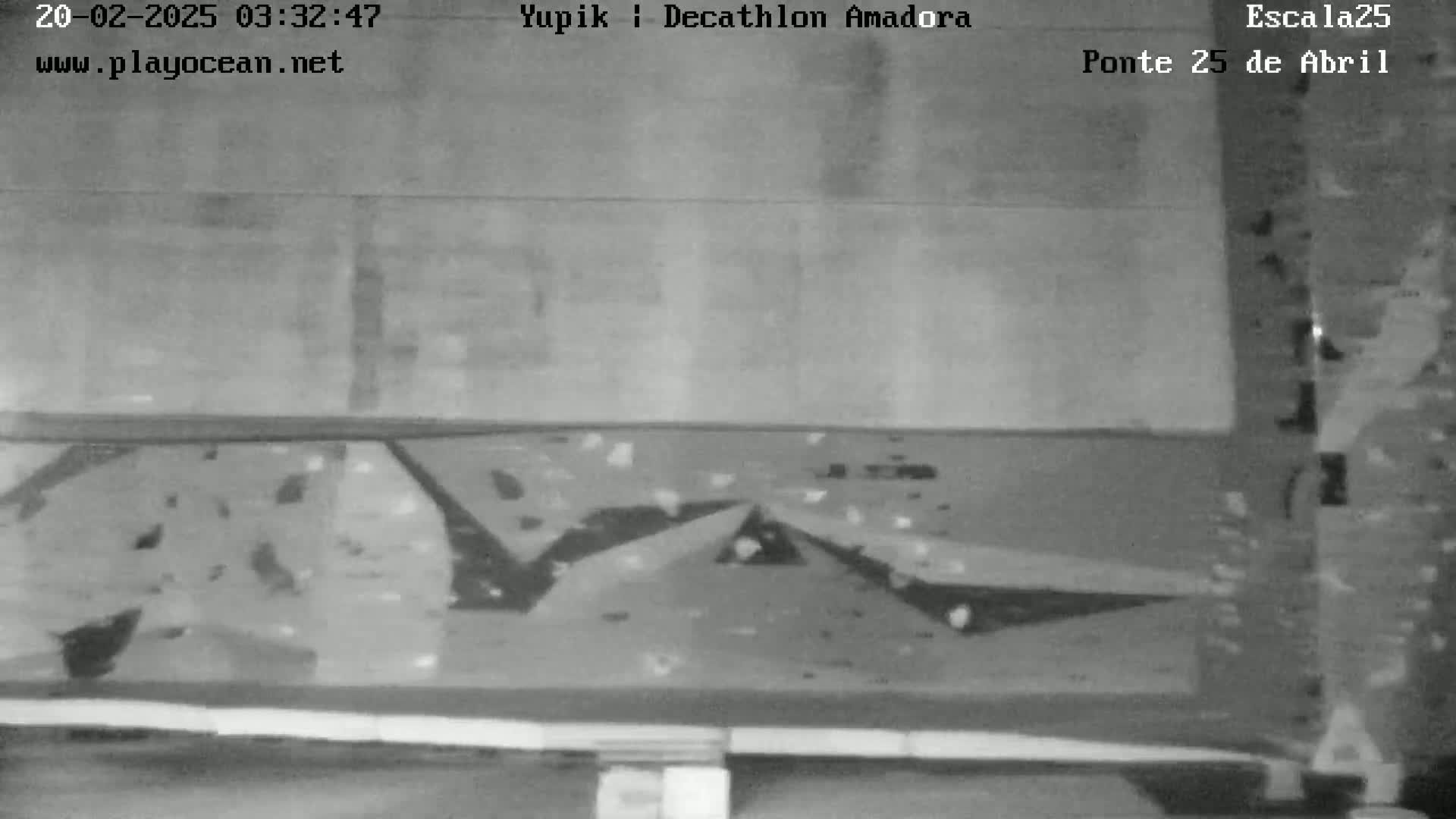 A grainy, black-and-white image shows a low-resolution view of what appears to be an outdoor climbing wall at night.