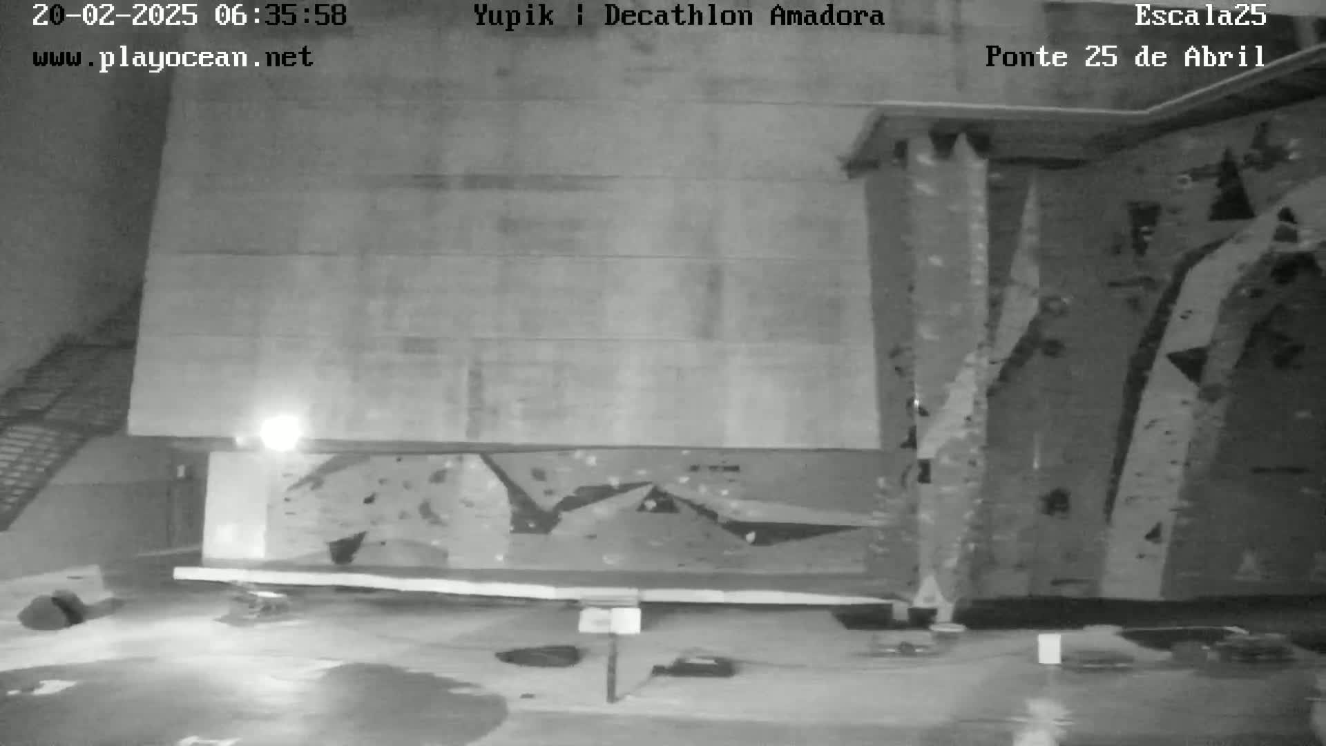 A dark indoor space features a climbing wall and a wet floor.