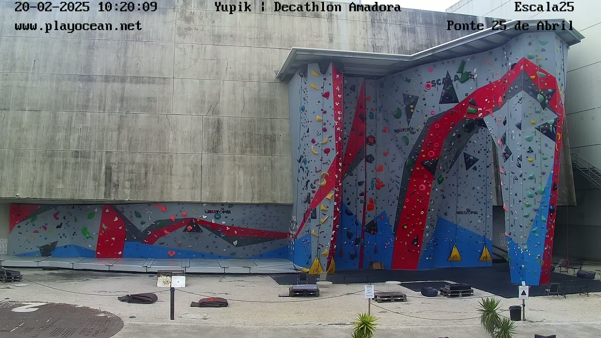 An outdoor, overcast-day view of a large, multi-colored climbing wall attached to a building.