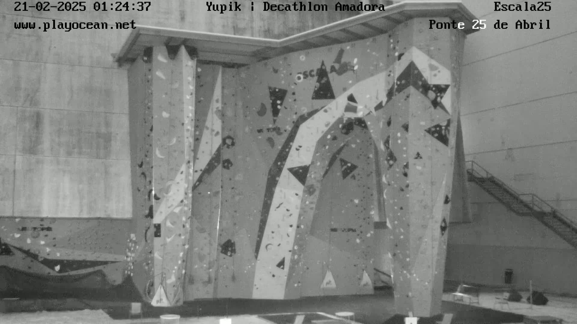 An indoor climbing wall with various holds and patterns is shown in a black and white image.