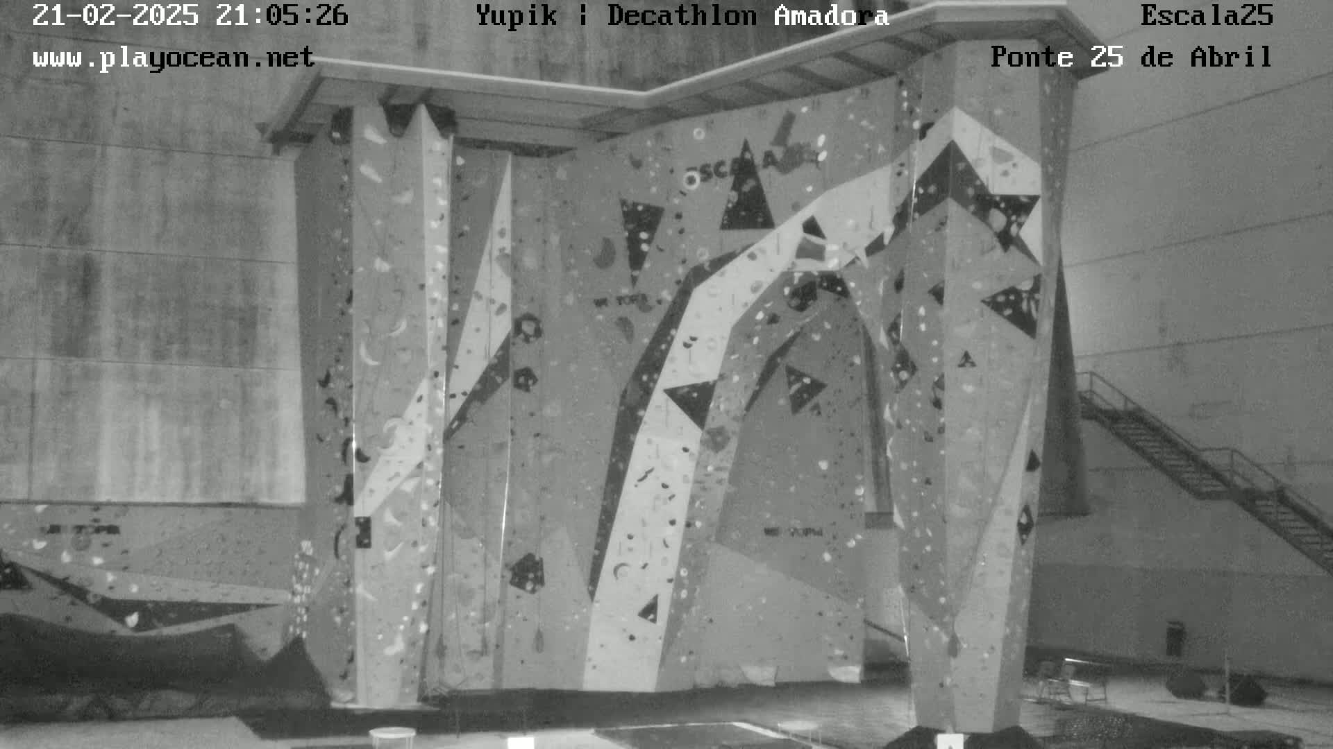 A large indoor climbing wall with various holds and patterns is shown in a grayscale image.
