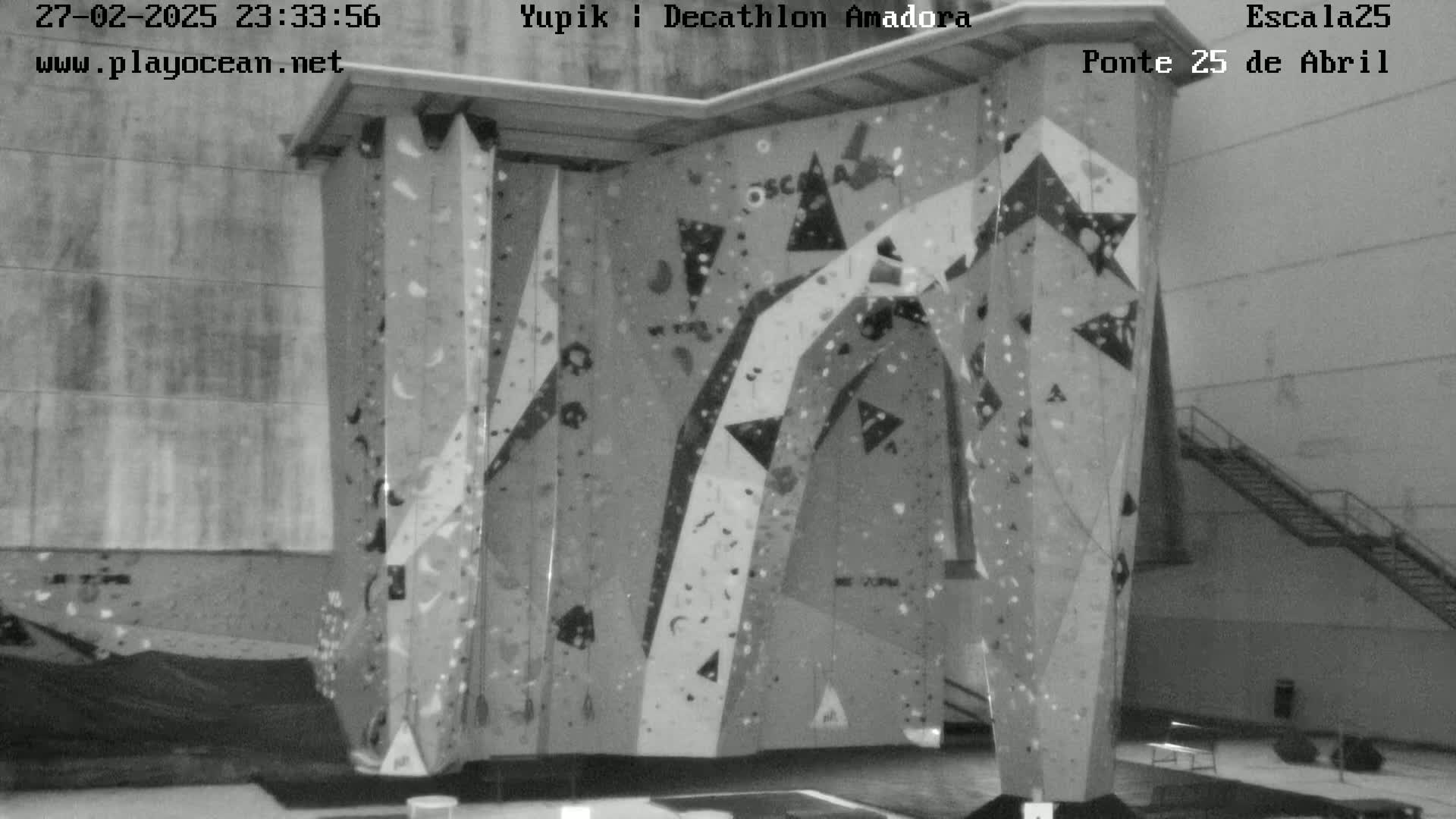 A large indoor climbing wall with various holds is shown in a grayscale image.