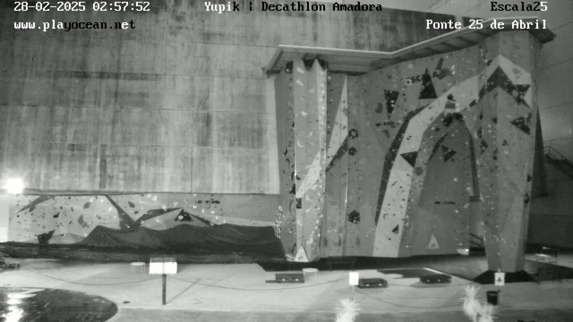 A grayscale image shows an indoor rock climbing wall at night.