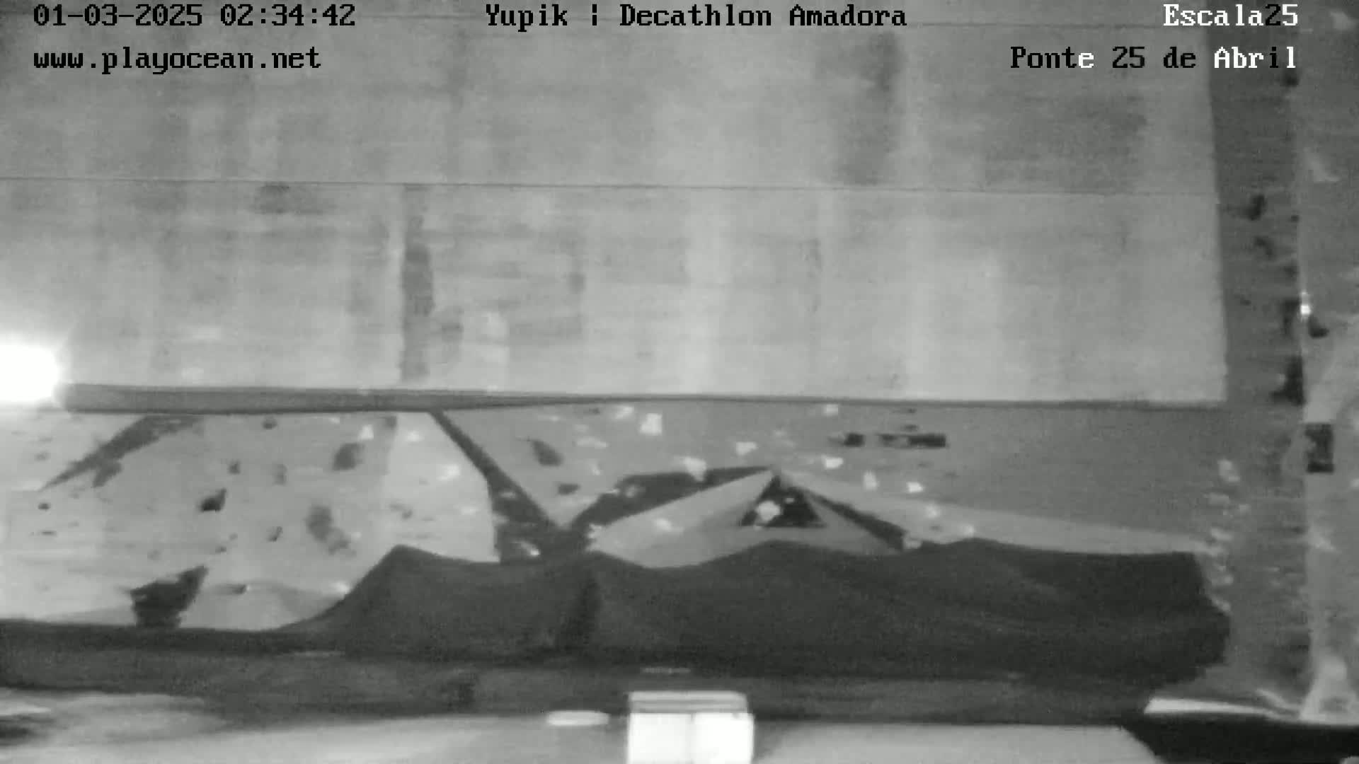 A low-light grayscale image shows a dark, textured surface with several triangular shapes spread across it.